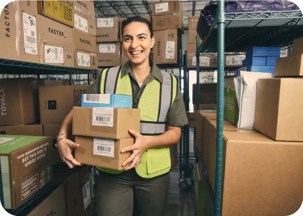A female Veho employee picking some packages from racks in the warehouse.