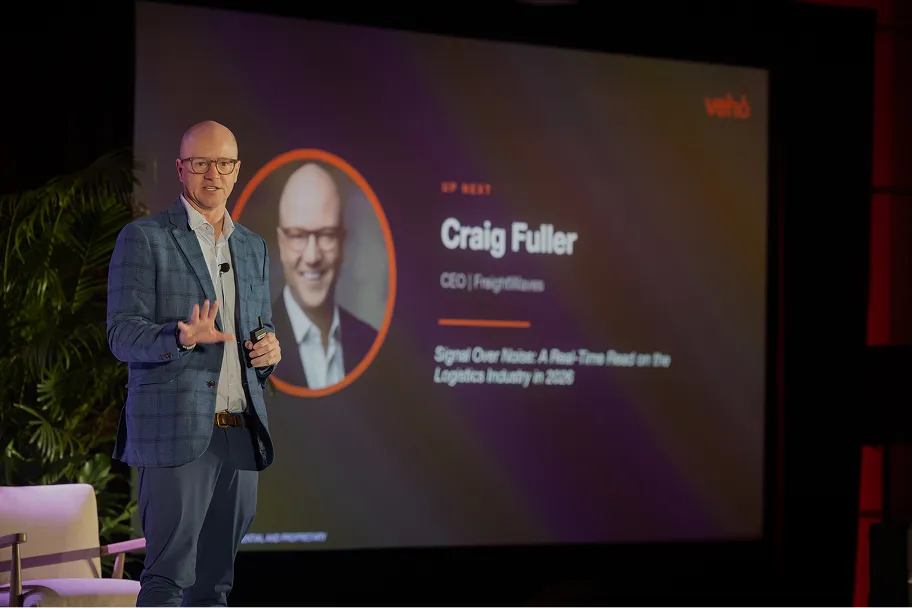 Craig Fuller, CEO of FreightWaves, speaking on stage with a presentation slide behind him.